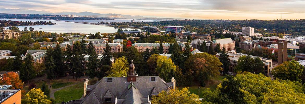 An aerial photo above Denny Hall on the UW campus with a distant Seattle skyline