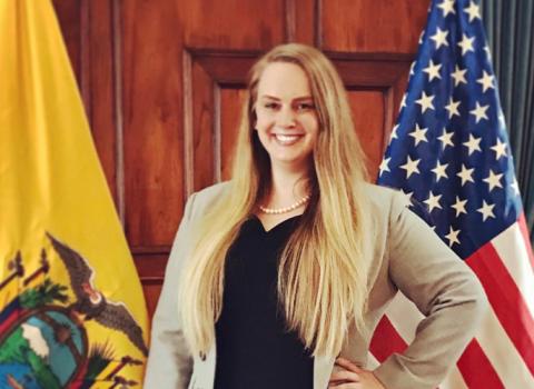 Amanda Tollefson smiling next to the American and Ecuadorian flags