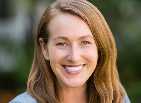 Maureen Trantham smiling in front of a soft dark green background.