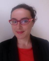 Professor Clare, wearing red glasses, in front of a grey background