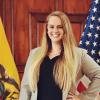 Amanda Tollefson smiling next to the American and Ecuadorian flags
