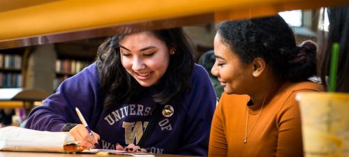 Two young women writing answers to a Harry Potter Trivia contest in the library